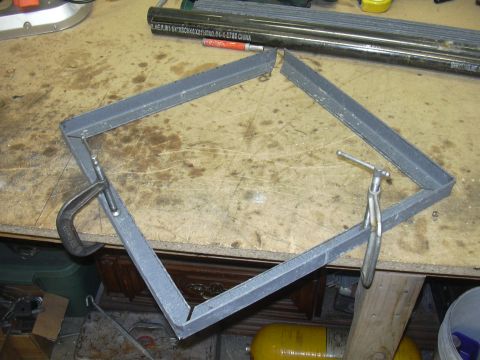 1991 Ford Bronco - A metal frame is being held together with clamps on a workbench, with various tools and materials in the background.