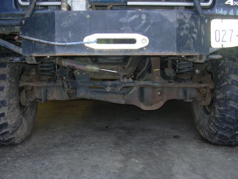 1991 Ford Bronco - Close-up view of the front axle and suspension components of a modified off-road vehicle.