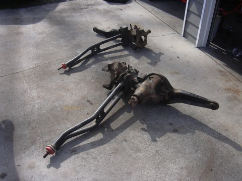 1991 Ford Bronco - Two vehicle axle assemblies are laid out on a concrete driveway, possibly for repair or modification.