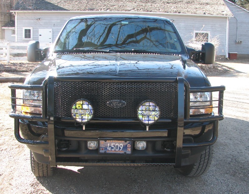 Black 2003 Ford Excursion with a black grille guard and two PIAA lights, viewed from the front