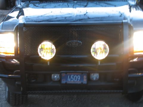 2003 Ford Excursion - Front view of a black Ford truck's grille, equipped with auxiliary lights and a license plate.