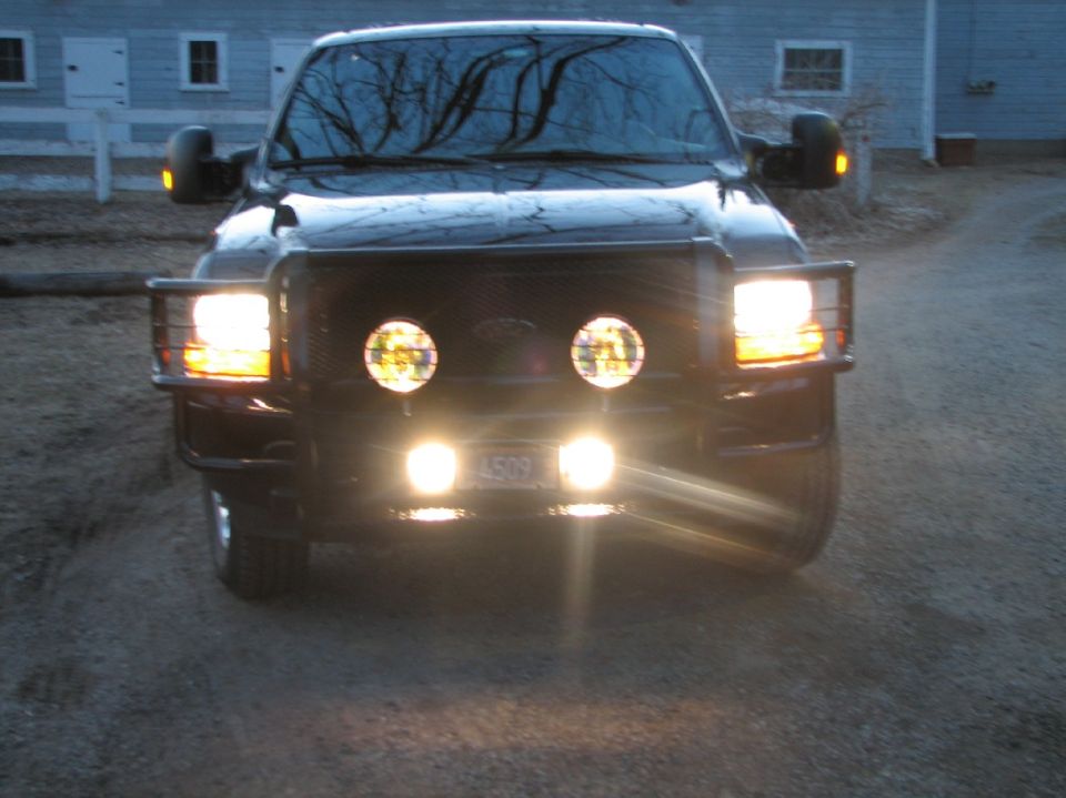 Dark Ford SUV at dusk with grille guard and round auxiliary driving lights lit
