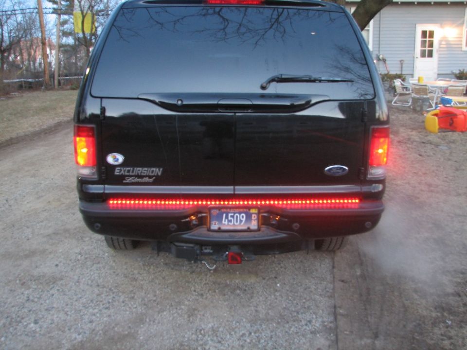 Rear of black 2003 Ford Excursion with aftermarket red LED light bar and 'EXCURSION Limited' badging