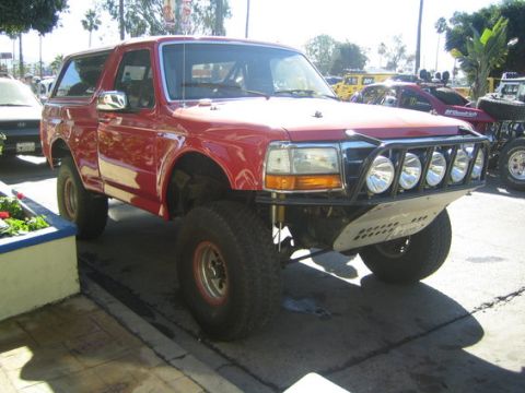 1984 Ford Bronco - This modified Ford Bronco features a custom front bumper with multiple spotlights and oversized tires.