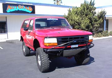 1984 Ford Bronco - This red Ford Bronco is parked in front of a building with a sign that says 'AUTOPAD'.