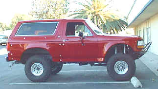 1984 Ford Bronco - This red Ford Bronco appears to be from the early 1980s, with modifications to its suspension and bumper.