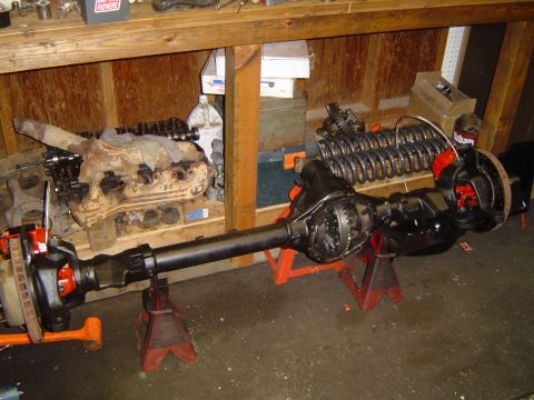 1989 Ford Bronco - A vehicle axle assembly is shown on jack stands, with an engine and other parts in the background.