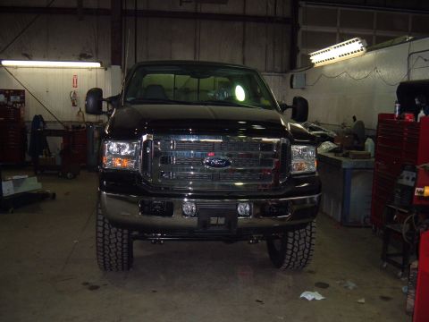 1979 Ford Bronco - Front view of a black Ford Super Duty truck inside a workshop.