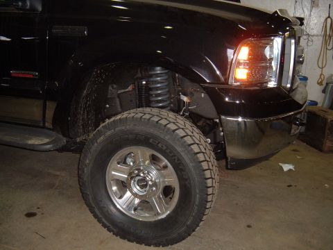 1979 Ford Bronco - Close-up view of the front wheel and fender assembly of a black pickup truck.