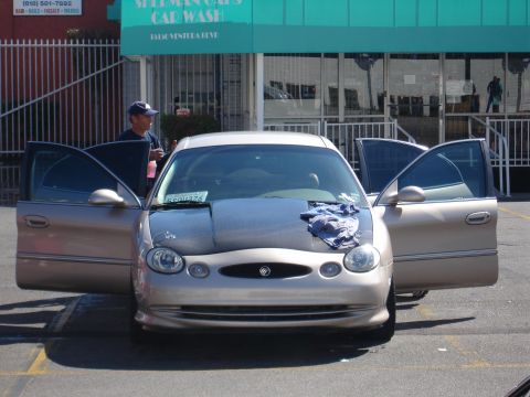 1993 Ford Taurus - Gold sedan parked outside a car wash with all doors open.
