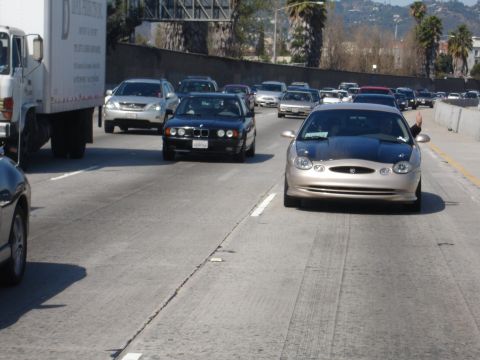 1993 Ford Taurus - A gold Ford Taurus with a black hood is seen driving on a busy highway.