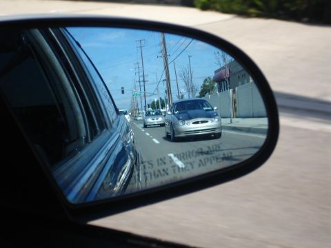1993 Ford Taurus - A silver sedan is reflected in the side mirror of another vehicle, showing a front view of the car. The text 'Objects in mirror are closer…