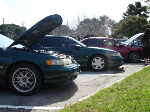 1993 Ford Taurus - Multiple vehicles are parked in a lot, with two of them having their hoods open.