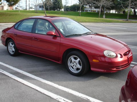 1993 Ford Taurus - This red sedan's body style indicates it is likely from the mid-to-late 1990s, not a 1993 model.