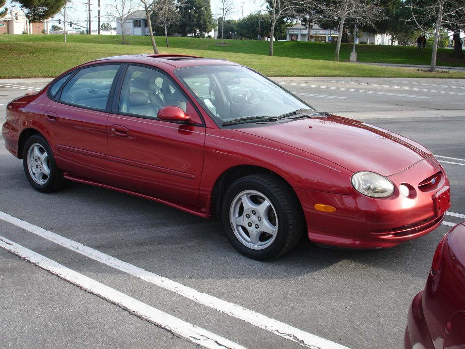 Red sedan, 3q front view. Body style suggests mid-to-late 1990s