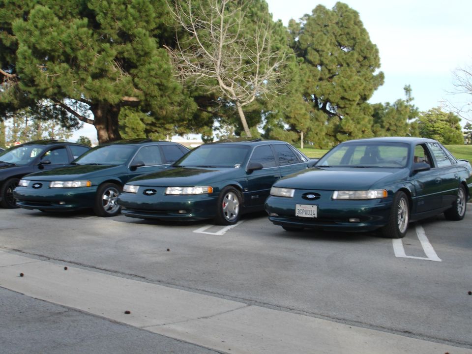 Three dark green 1993 Ford Tauruses parked side-by-side, front view