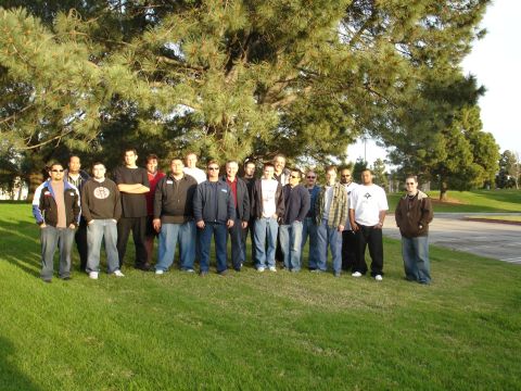1993 Ford Taurus - A group of men pose for a photo outdoors, standing on a grassy hill with a large pine tree behind them.