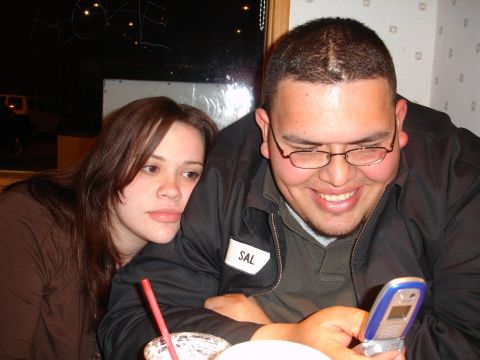 1993 Ford Taurus - A man and woman interact with a flip phone indoors.