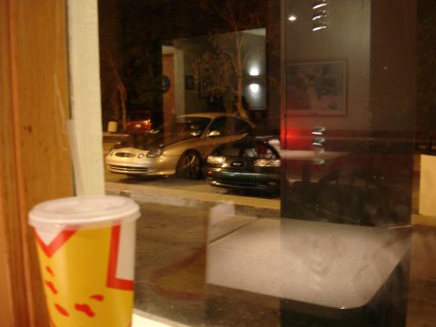 1993 Ford Taurus - Two cars are parked outside at night, seen through a window with a drink cup in the foreground.