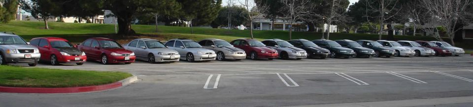 Silver sedan with a black hood parked in a lot with other cars