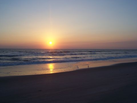 1994 Ford Probe - The sun sets over the ocean, casting a golden reflection on the water and wet sand.