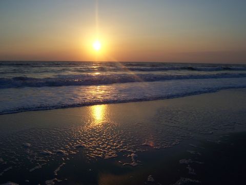 1994 Ford Probe - A beautiful sunset casts a golden glow over the ocean waves as they meet the shore.