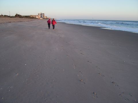 1994 Ford Probe - Two figures stroll along the shoreline as waves crash gently on the sand.