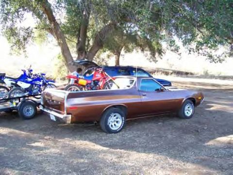 1972 Ford Ranchero - A brown pickup truck is parked outdoors, with a trailer carrying dirt bikes behind it.
