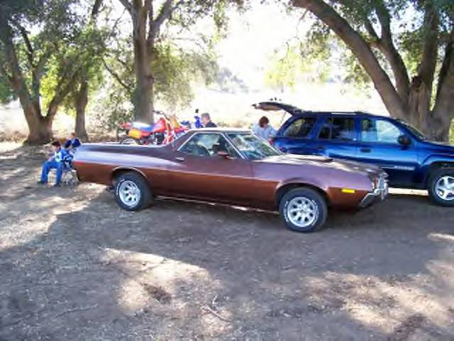 Brown Ford Ranchero coupe utility parked in profile on dirt under trees