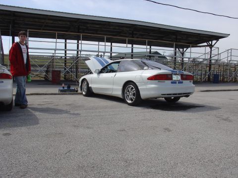 1993 Ford Probe - White 1993 Ford Probe with blue racing stripes, hood open, parked at a track with bleachers in the background.