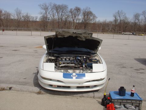 1993 Ford Probe - A white 1993 Ford Probe is parked outside with its hood open, revealing the engine bay. Tools and drinks are on a tray next to the car.