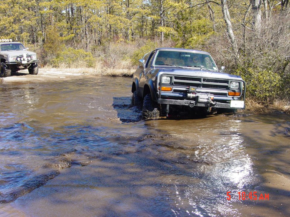 Dark blue Dodge Ram pickup truck with a winch on the front bumper driving through shallow water