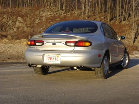 1999 Ford Taurus - This silver 1999 Ford Taurus is viewed from the rear, showing its distinctive taillights and spoiler.