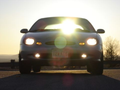 1999 Ford Taurus - The front of a 1999 Ford Taurus is shown with the sun directly overhead, creating lens flare.