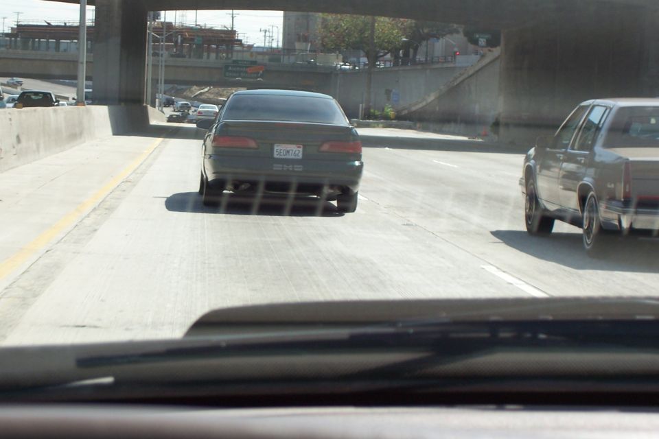 Dark sedan driving on highway, another car to the right. License plate visible