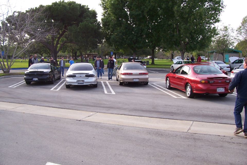 Red sedan parked in a lot, rear view, with a spoiler and a license plate