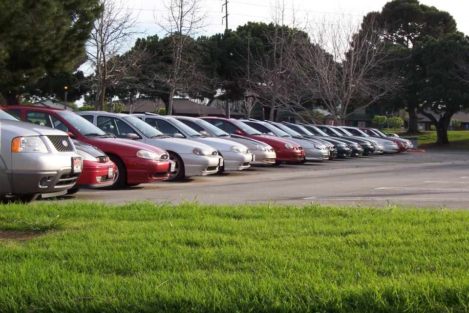 Silver sedan with a red car behind it, parked in a row on asphalt