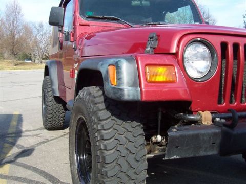 1998 Jeep TJ - Front view of a red Jeep Wrangler with off-road tires and black rims.