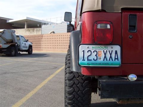 1998 Jeep TJ - A red Jeep Wrangler is parked in a lot, with another truck visible in the background.