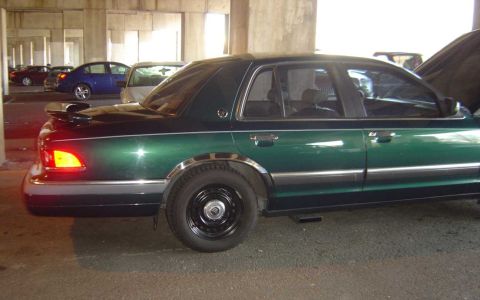 1998 Ford Crown Victoria - Side view of a green 1998 Ford Crown Victoria with a spoiler and chrome trim.