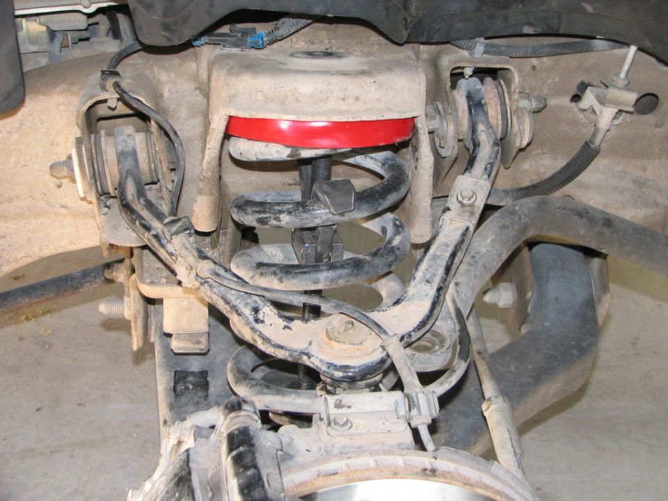 Underside view of front coil spring suspension with spring compressor tool installed