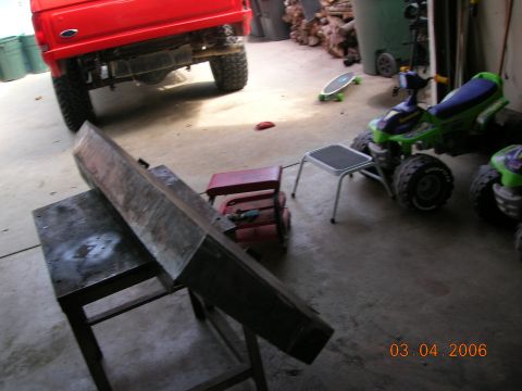 1985 Ford Bronco - The rear bumper of a red 1985 Ford Bronco is visible in this garage scene.