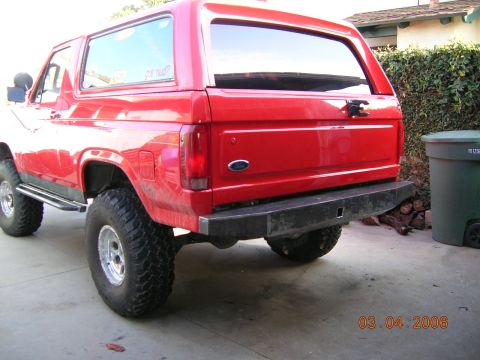 1985 Ford Bronco - Rear view of a red Ford Bronco with an aftermarket bumper and off-road tires.