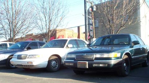 1998 Ford Crown Victoria - A dark green 1998 Mercury Grand Marquis is parked next to a white car.