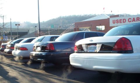1998 Ford Crown Victoria - Several sedans, including a 1998 Ford Crown Victoria, are lined up at a used car dealership.