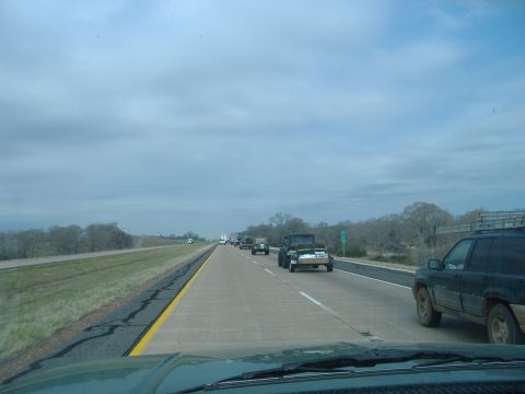 2004 Jeep Wrangler - Multiple vehicles, including a Jeep TJ, travel on a highway under a cloudy sky.