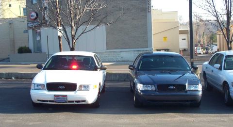 1998 Ford Crown Victoria - Two Ford Crown Victoria police cars are parked next to each other on a street.