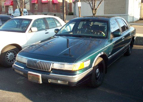 1998 Ford Crown Victoria - Front view of a green Mercury Grand Marquis parked outdoors next to another vehicle.