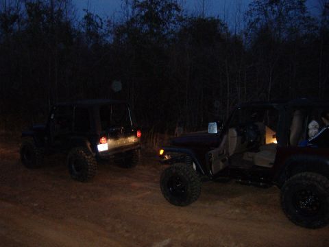 2004 Jeep Wrangler - Two Jeep Wranglers are parked on a dirt road at dusk, with one vehicle's doors open.