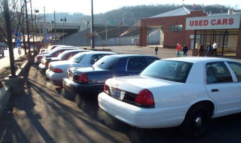 1998 Ford Crown Victoria - Several Ford Crown Victorias are parked in front of a used car dealership.